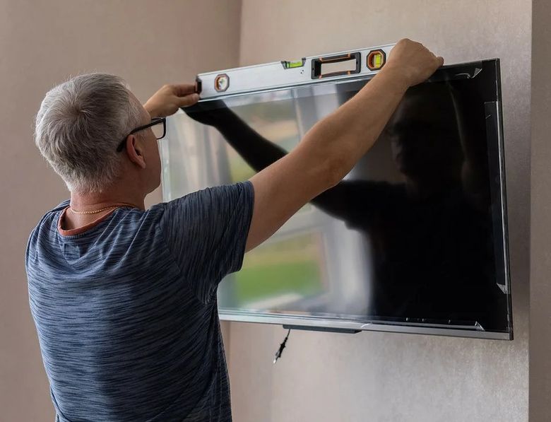 Installer checking a mounted TV with a level